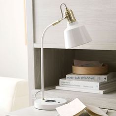 a white lamp sitting on top of a desk next to books