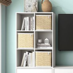 a white bookcase with baskets and a television