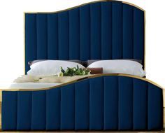 an upholstered blue bed with gold trimmings and white pillows on it