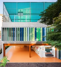 a building with multicolored panels on it's side and trees in the foreground