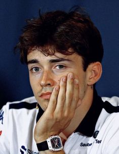 a close up of a person with a watch on his wrist and hand near his face