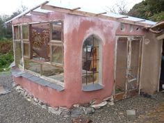 a small pink building sitting on top of a gravel field