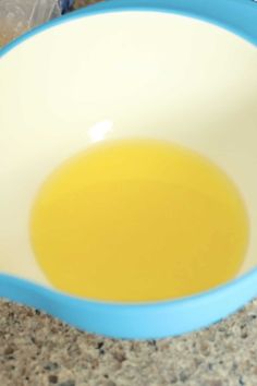 a blue and white bowl with yellow liquid in it sitting on a counter next to a plastic bag