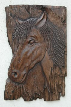 a wood carving of a horse's head on a white wall