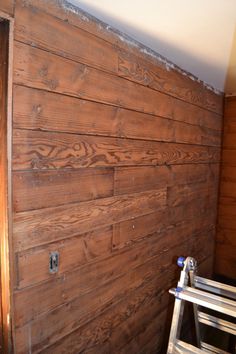 a wood paneled wall with a ladder next to it and some paint on the walls