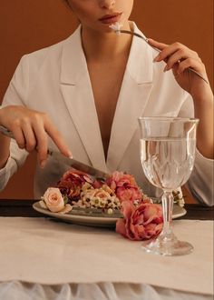 a woman eating food with a fork and glass on the table in front of her