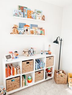 a white book shelf filled with lots of books and stuffed animals on top of it