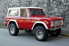 a red and white truck parked next to a stone wall