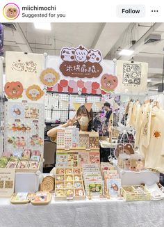 a woman standing in front of a table filled with items