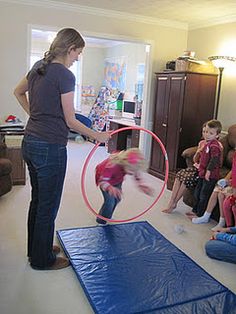 a woman standing on top of a blue mat while holding a red hula hoop