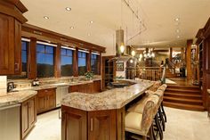 a large kitchen with marble counter tops and wooden cabinets, along with stairs leading up to the second floor