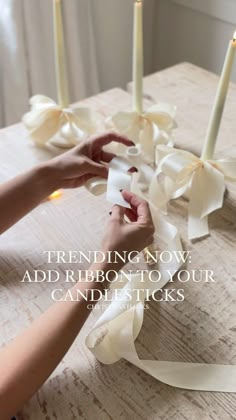 someone decorating a table with candles and paper flowers on it that reads, trending now add ribbon to your candlesticks