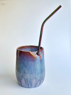 a blue cup with a straw sticking out of it's side on a white surface