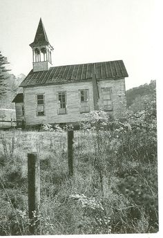 an old abandoned building with a steeple on top and a fence in the foreground