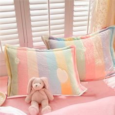 a teddy bear sitting on top of a bed next to two pillows and a pillow case