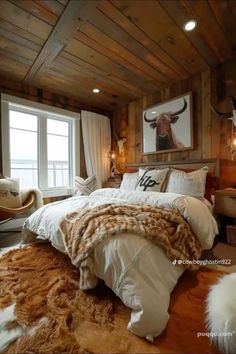 a large bed sitting in a bedroom next to a window and cow head on the wall