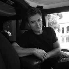 a black and white photo of a man sitting in the back seat of a truck