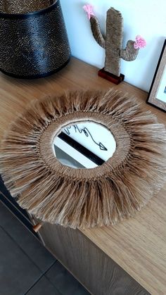 a mirror that is sitting on top of a wooden table next to a potted cactus