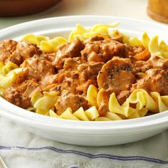 pasta with meat and sauce in a white bowl on a blue and white table cloth