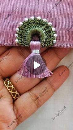 a hand holding a pink purse with a tassel on it and a video in the middle