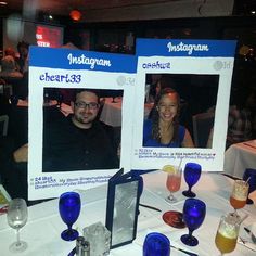 two people sitting at a table with wine glasses and photos on the tables in front of them