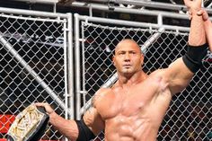 a man standing in front of a metal fence holding a wrestling glove up to his head