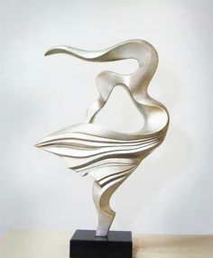 a metal sculpture sitting on top of a wooden table in front of a white wall