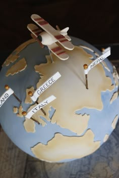 a small model airplane sitting on top of a blue and white globe with name tags