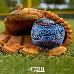 a catchers mitt with a dragon's logo on it sitting in the grass