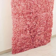 a large pink flowered wall hanging on the side of a white wall in an empty room