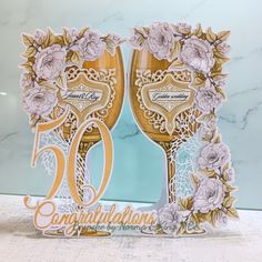 two champagne glasses with flowers and the words congratulations written on them are surrounded by gold foil