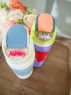 two plastic containers sitting on top of a wooden table with flowers in the back ground