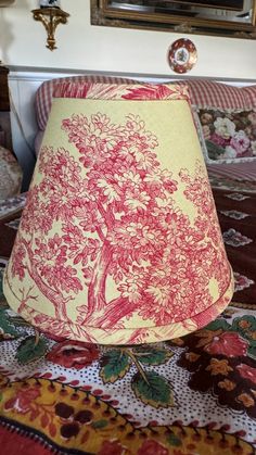 a red and white lamp shade sitting on top of a bed