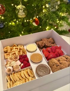 a white box filled with lots of different types of food next to a christmas tree