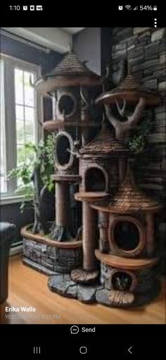 a cat tree in the middle of a room with windows and plants on top of it