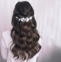 the back of a woman's head with long hair and flowers in her hair