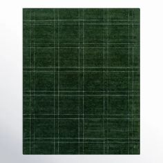 a square green rug with white lines on the top and bottom, placed in front of a wall