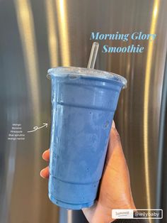 a hand holding a blue drink in front of a metallic refrigerator with the words morning glory smoothie on it