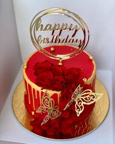 a red and gold birthday cake with roses on the bottom is decorated with a butterfly