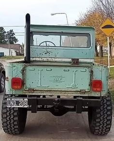 an old truck is parked on the side of the road in front of another car