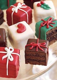 there are many different types of cakes on the glass platter with red, green and white frosting