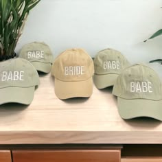 three hats that say babe, babe and babe on them sitting on a table next to a potted plant