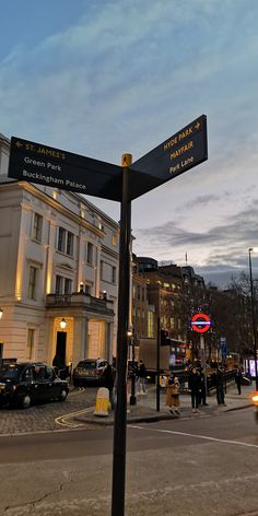 a street sign that is on the side of a road with people walking around it