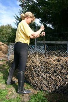 a woman in black pants and yellow shirt holding a baseball bat near a chain link fence