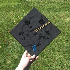 a hand holding a graduation cap with flowers on it