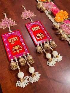 two red and gold earrings sitting on top of a wooden table next to each other