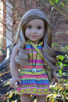 a doll with blonde hair wearing a colorful dress and carrying a brown purse in her hand