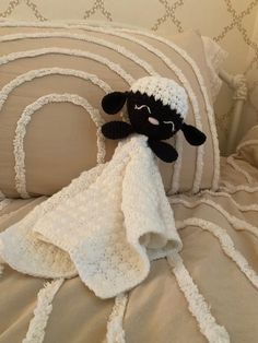 a black and white stuffed animal laying on top of a bed next to pillows with ruffled edges