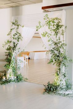 an indoor wedding venue decorated with greenery and white drapes