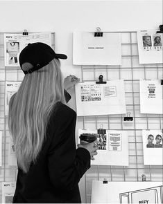 a woman standing in front of a wall covered with papers and post - it notes